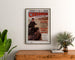Vintage-Normandie-Poster – Cherbourg, Chemins de fer de l’Ouest, gerahmt über einer Kommode aus Holz, zwischen Pflanzen.