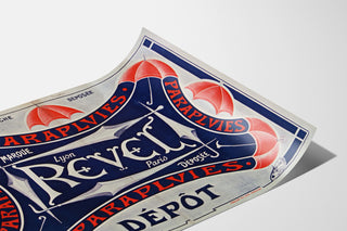 Plakat Parapluies Revel — eingetragene Marke, Lyon, Paris, auf leicht gewölbtem Papier in Perspektive präsentiert.
