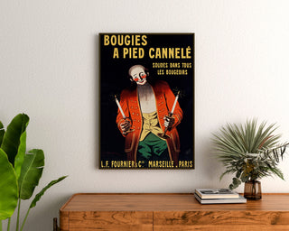 Vintage-Werbeplakat "Bougies Fournier", gerahmt über einer Holzkommode, zwischen Pflanzen.