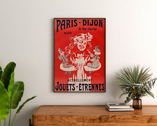 Vintage-Werbeplakat Paris–Dijon, Spielzeug und Neujahrsgeschenke, gerahmt über einer Holzkommode, zwischen Pflanzen.