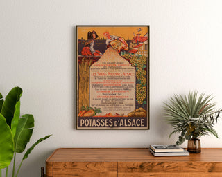 Vintage-Werbeplakat Potasses d’Alsace, gerahmt über einer Holzkommode zwischen Pflanzen.