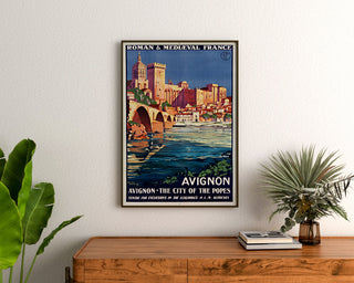 Vintage-Reiseplakat – Avignon, Roman & Mediaeval France, gerahmt über einer Holzkommode zwischen Pflanzen.