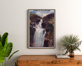 Vintage-Tourismusplakat – Gimel, la Grande Cascade, gerahmt über einer Holzkommode, zwischen Pflanzen.