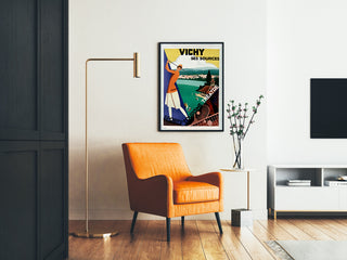 Vintage-Reiseposter – Vichy, Quellen und Tourismus, gerahmt in einem Wohnzimmer mit orangefarbenem Sessel und Stehlampe.