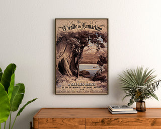 Vintage-Plakat «Aix-les-Bains, Grotte de Lamartine», eingerahmt über einer Holzkommode, zwischen Pflanzen.