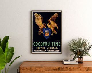 Vintage-Plakat „Cocofruitine, pflanzliche Butter“ gerahmt über einer Holzkommode, umgeben von Pflanzen.