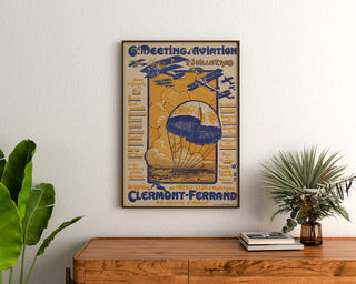 Vintage-Plakat Flugmeeting, Clermont-Ferrand, gerahmt über einer Holzkommode, zwischen Pflanzen.